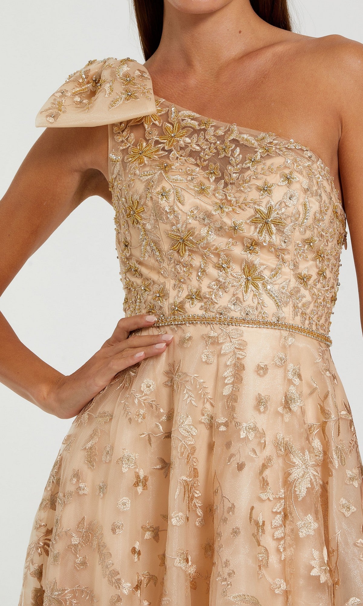 A woman wearing the Sage One-Shoulder Formal Dress (Mac Duggal 11177), featuring beaded floral embroidery and a decorative bow on the shoulder.